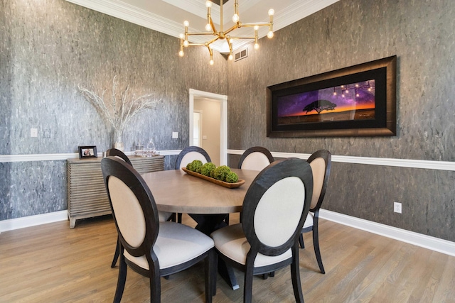 dining space with baseboards, ornamental molding, wood finished floors, and an inviting chandelier