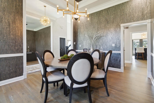 dining room featuring a high ceiling, a chandelier, wood finished floors, and ornamental molding