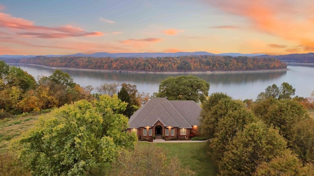 aerial view at dusk featuring a water view and a forest view