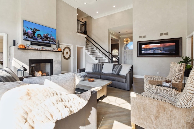 living area featuring crown molding, visible vents, stairway, a high end fireplace, and wood finished floors