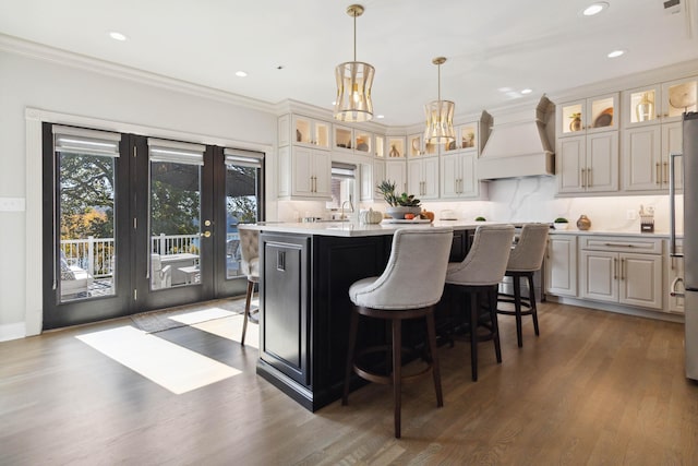 kitchen with light countertops, a kitchen island, custom exhaust hood, and a healthy amount of sunlight