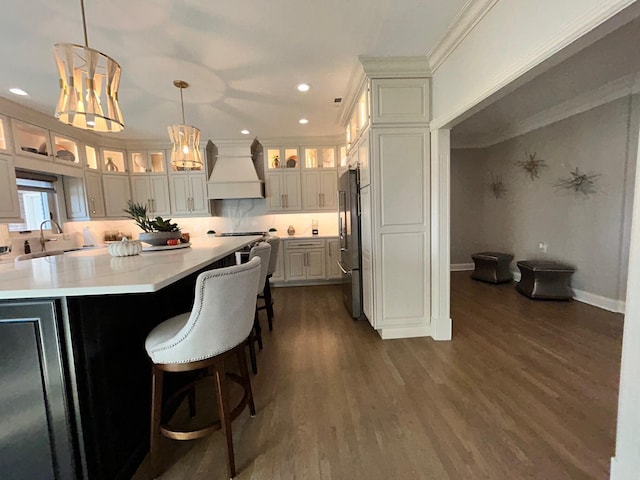 kitchen featuring dark wood-style floors, custom exhaust hood, light countertops, a sink, and high end refrigerator