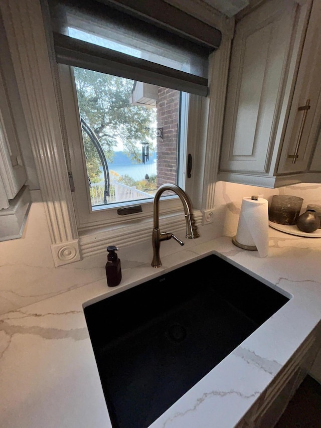 room details featuring light stone counters, a sink, and tasteful backsplash