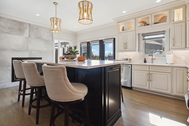 kitchen with a center island, crown molding, light countertops, stainless steel dishwasher, and a sink