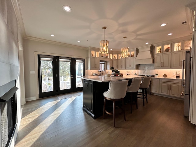 kitchen featuring decorative backsplash, custom range hood, a kitchen island, light countertops, and crown molding