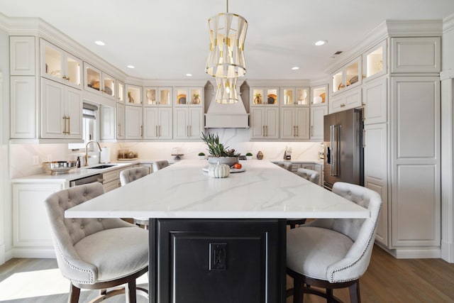 kitchen with high quality fridge, a kitchen island, a sink, and a kitchen breakfast bar