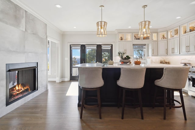 kitchen with a kitchen island, dark wood-type flooring, light countertops, crown molding, and a fireplace