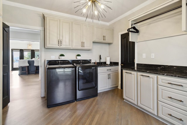 laundry area featuring separate washer and dryer, a sink, ornamental molding, cabinet space, and an inviting chandelier