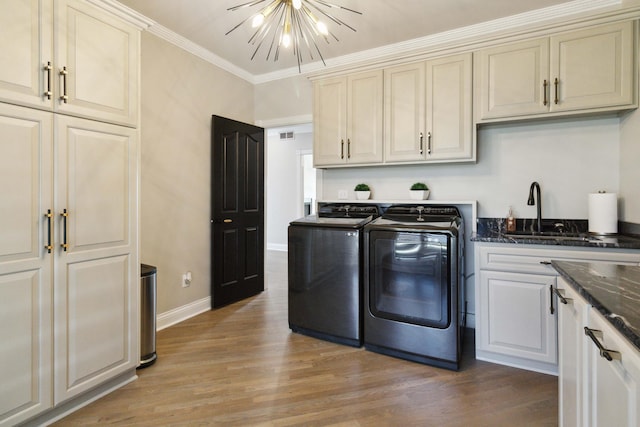 laundry area with a chandelier, a sink, ornamental molding, cabinet space, and washing machine and clothes dryer