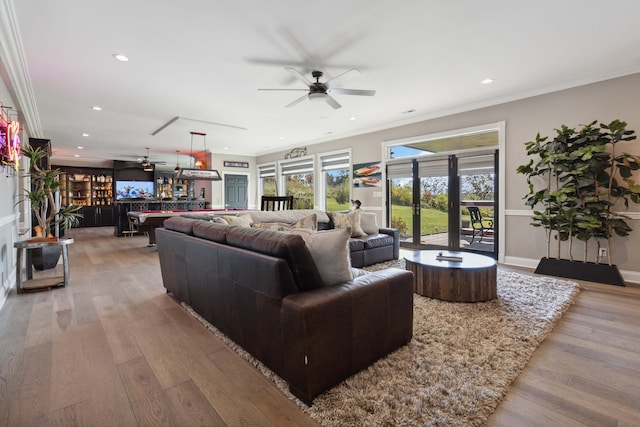 living room with ornamental molding, wood finished floors, and a ceiling fan