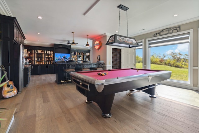 rec room featuring light wood-type flooring, bar area, crown molding, and recessed lighting