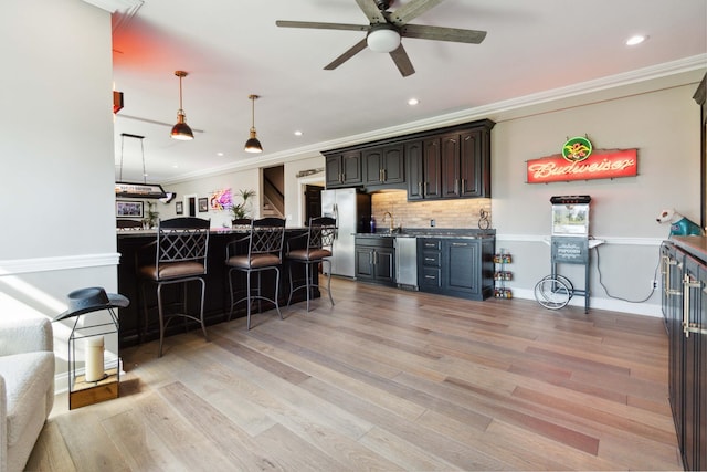 kitchen featuring a breakfast bar, crown molding, stainless steel refrigerator with ice dispenser, backsplash, and light wood-style floors