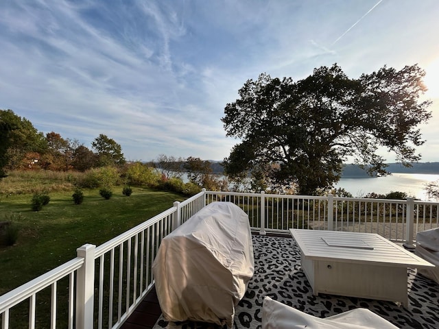 wooden terrace with a water view, a lawn, and area for grilling