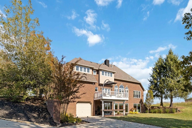 view of front of property with concrete driveway, brick siding, a balcony, and a front lawn