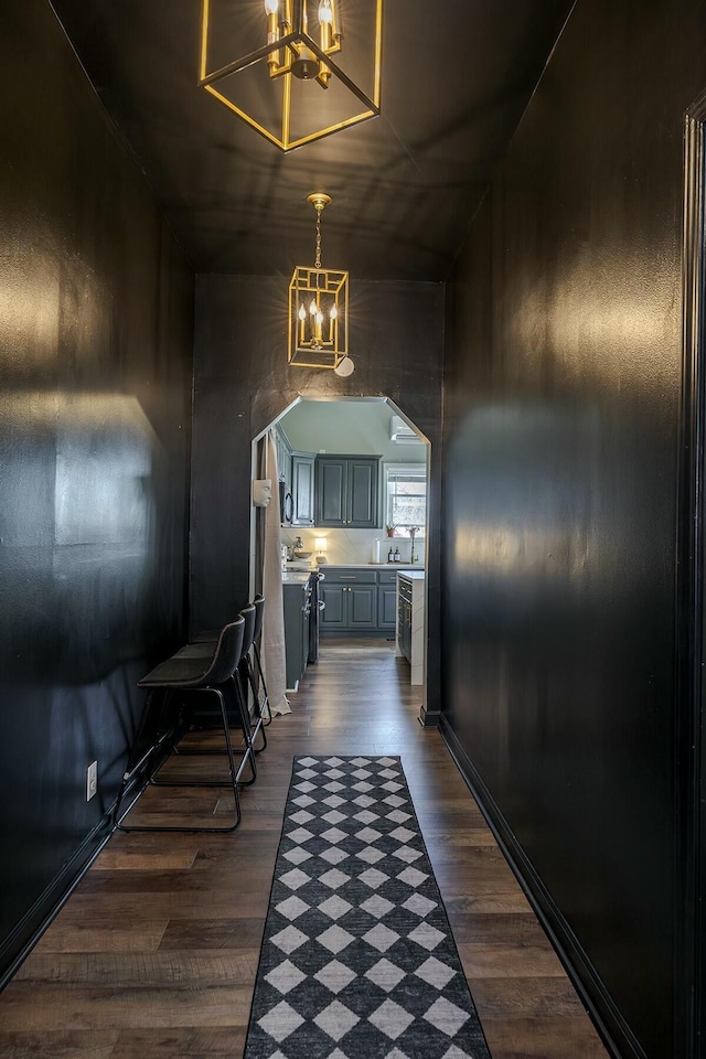 corridor with a chandelier, arched walkways, and dark wood-style floors