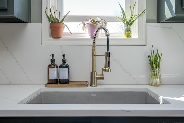 interior details featuring light stone counters and a sink