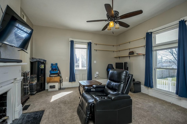 interior space with carpet floors, baseboards, a fireplace with flush hearth, and a ceiling fan