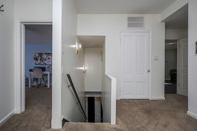 hall with carpet, baseboards, visible vents, and an upstairs landing