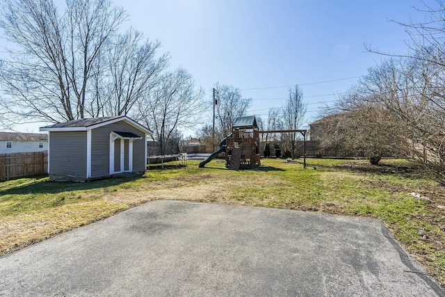 view of yard with a playground, an outdoor structure, fence, a storage unit, and a trampoline