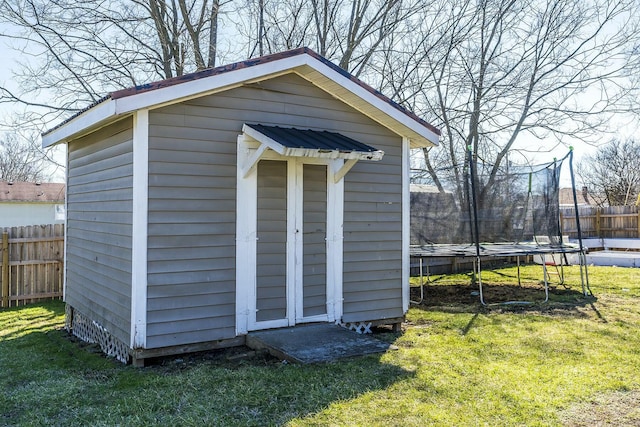 view of shed with a trampoline and fence