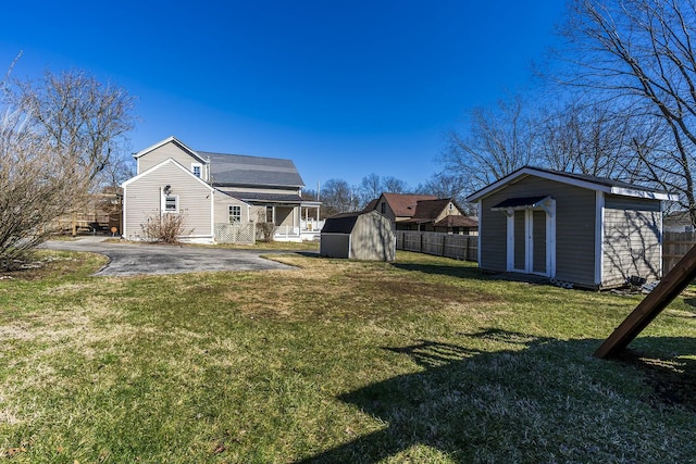 view of yard with an outbuilding, a patio area, fence, and a shed