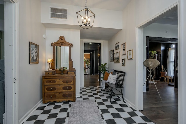 foyer featuring visible vents, dark floors, baseboards, and a notable chandelier