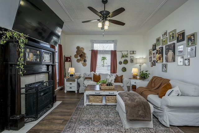 living room featuring a fireplace with flush hearth, a ceiling fan, and wood finished floors