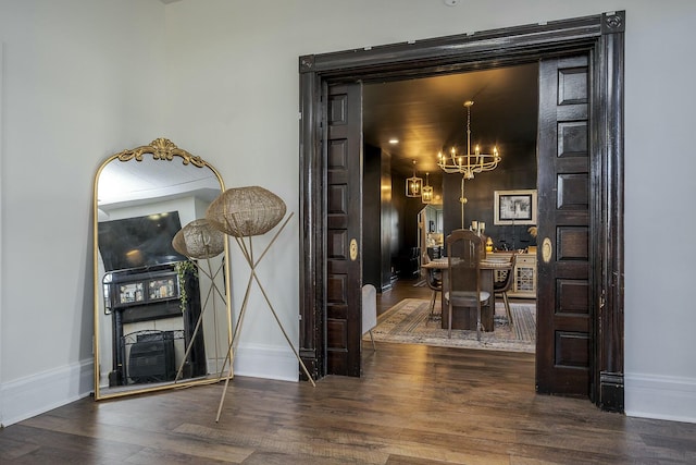 interior space with an inviting chandelier, baseboards, and wood finished floors