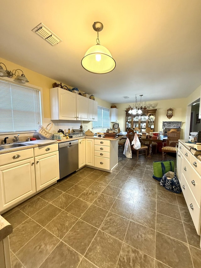 kitchen with pendant lighting, visible vents, stainless steel dishwasher, open floor plan, and a peninsula