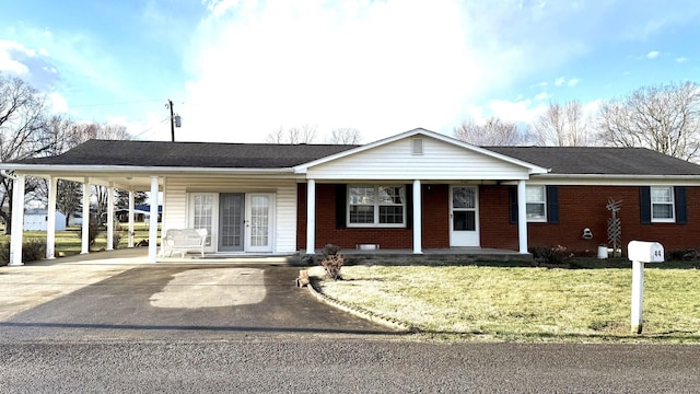 ranch-style house with brick siding, covered porch, a front yard, an attached carport, and driveway