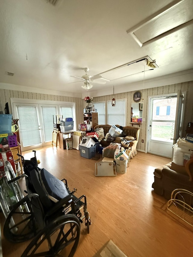 living area with crown molding, wood finished floors, attic access, and a ceiling fan