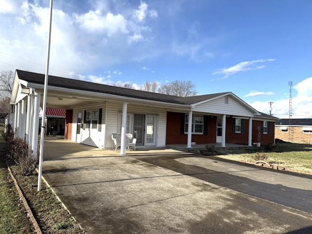 ranch-style home with a carport, concrete driveway, brick siding, and a porch