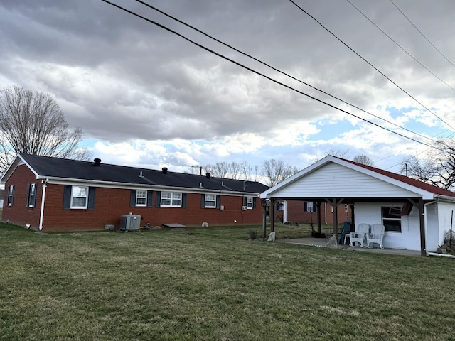 back of house featuring a patio, a lawn, cooling unit, and brick siding