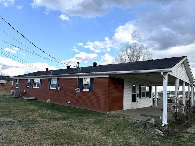 view of home's exterior featuring brick siding, a lawn, a patio area, cooling unit, and an attached carport