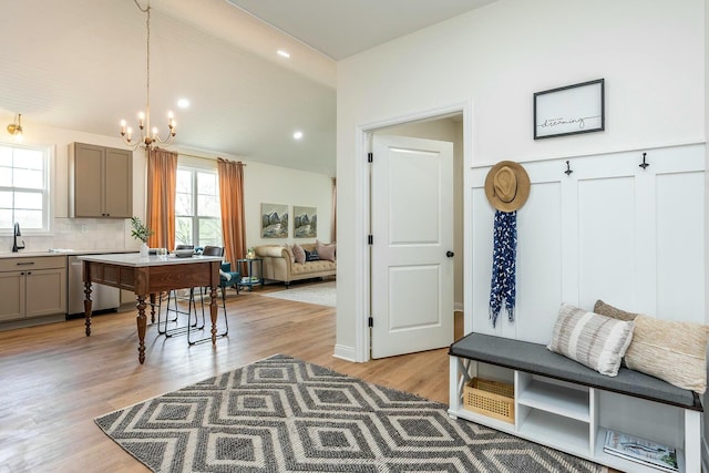 mudroom with lofted ceiling, light wood-style flooring, recessed lighting, a notable chandelier, and a sink