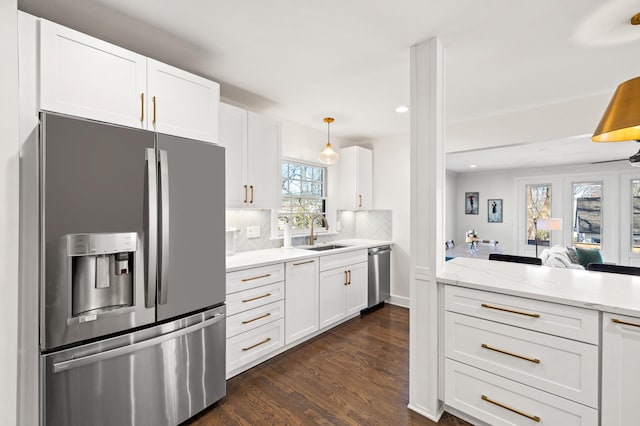 kitchen featuring white cabinets, dark wood-style flooring, a sink, stainless steel appliances, and backsplash