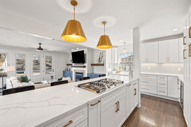 kitchen with white cabinets, dark wood finished floors, open floor plan, light stone countertops, and stainless steel gas stovetop