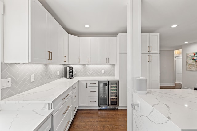 kitchen featuring light stone counters, beverage cooler, white cabinetry, and dark wood finished floors