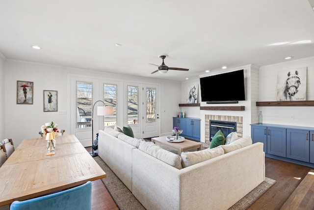 living area featuring dark wood finished floors, a fireplace, crown molding, recessed lighting, and a ceiling fan