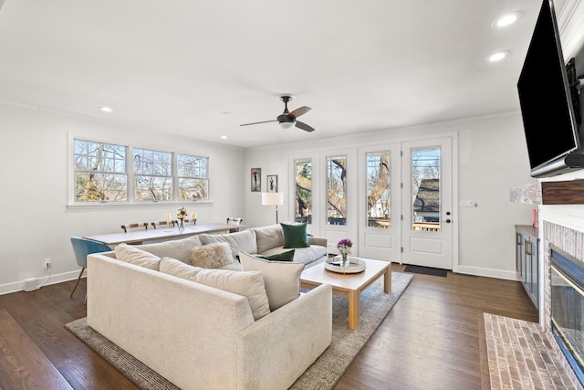 living room with dark wood-type flooring, recessed lighting, a tile fireplace, and baseboards