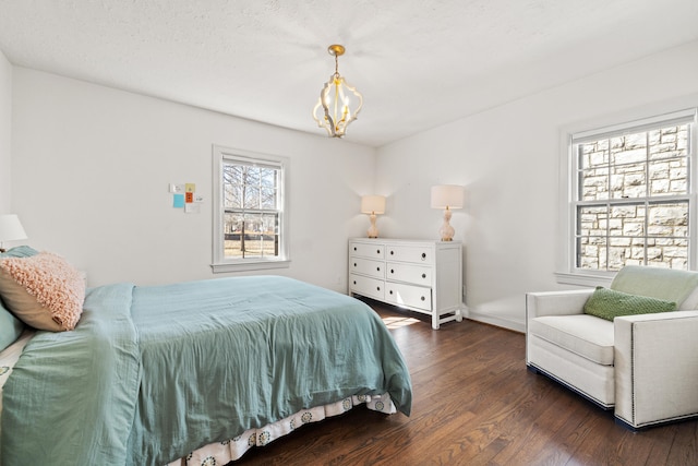 bedroom featuring baseboards, wood finished floors, and a notable chandelier