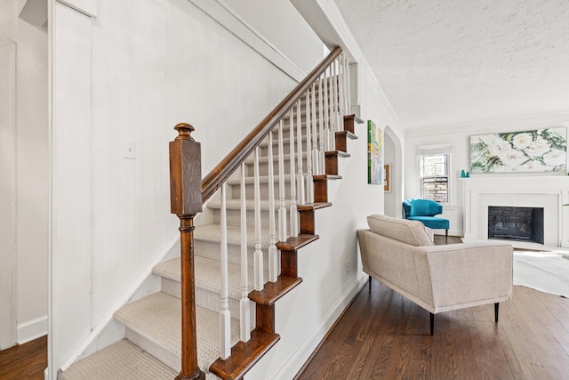 stairs with wood-type flooring, a fireplace, baseboards, and a textured ceiling