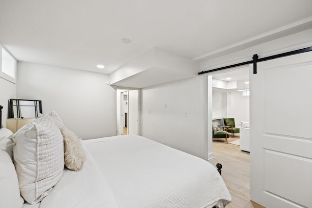 bedroom with light wood-type flooring, recessed lighting, and a barn door