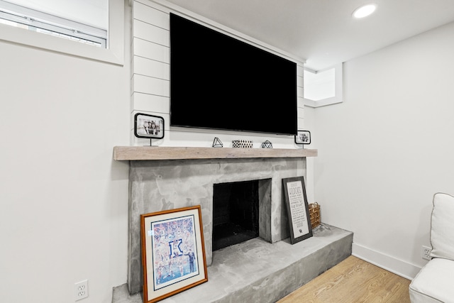 room details featuring baseboards, a fireplace with raised hearth, wood finished floors, and recessed lighting