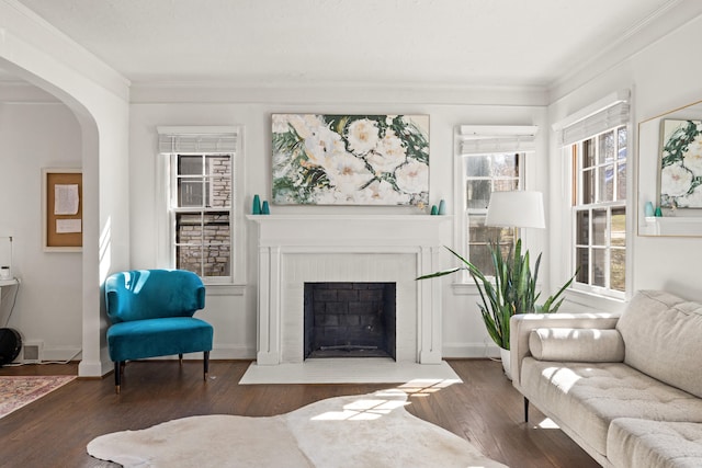 living area featuring ornamental molding, hardwood / wood-style floors, a brick fireplace, and baseboards