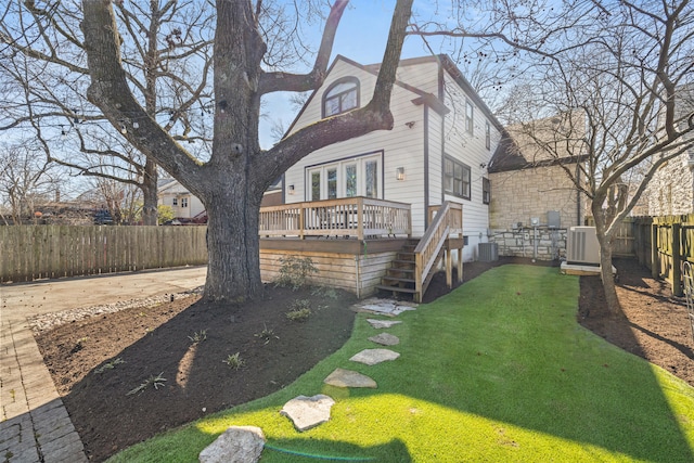 exterior space featuring central air condition unit, a fenced backyard, a deck, and a lawn