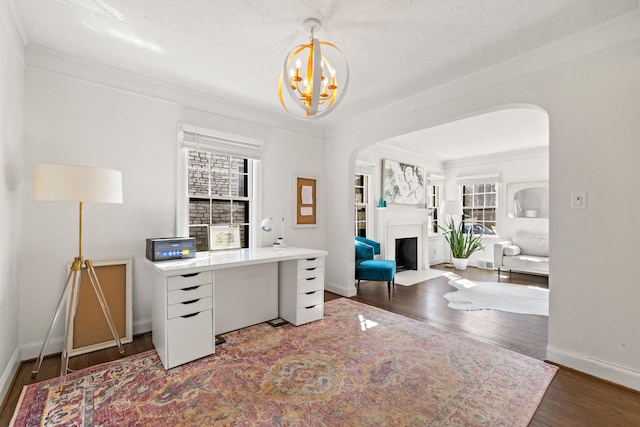 office space featuring ornamental molding, arched walkways, a fireplace, and wood finished floors