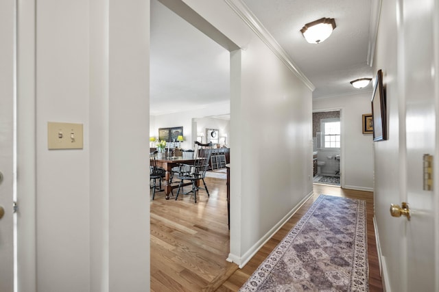 hall with baseboards, wood finished floors, and crown molding