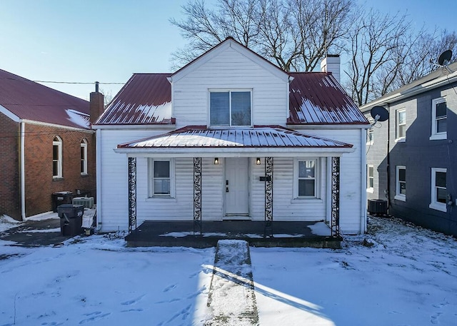 bungalow-style house with covered porch, metal roof, a chimney, and central air condition unit