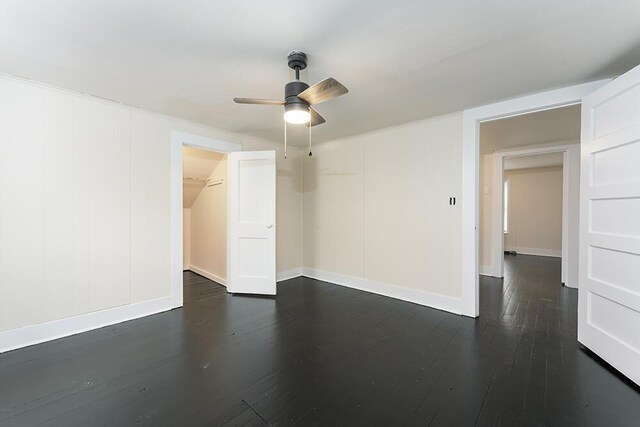 empty room with baseboards, visible vents, a ceiling fan, and dark wood-style flooring